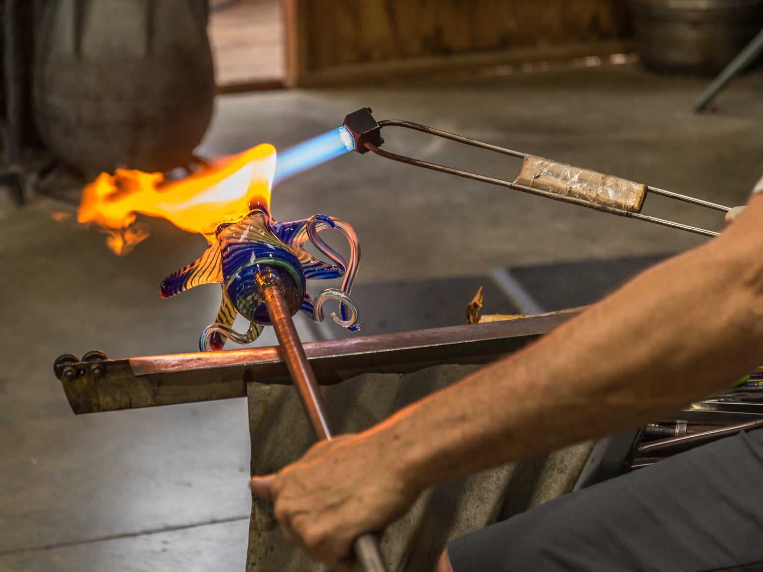 Hopko Art Glass blowing process of octopus with flames and glass on a metal rod.