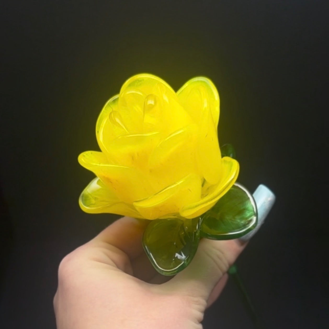 Hand holding a yellow flower-shaped light against a dark background