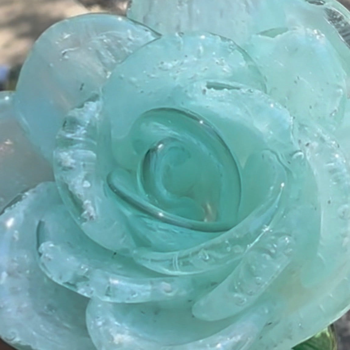 Clear glass rose with water droplets on a blurred background